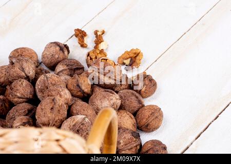 Stacked walnuts from basket on white wooden table - walnut harvest Stock Photo