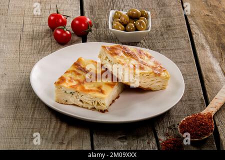 Water pastry on the plate. Composition of water pastry, tomato, hot pepper and olives on old wooden table. Stock Photo