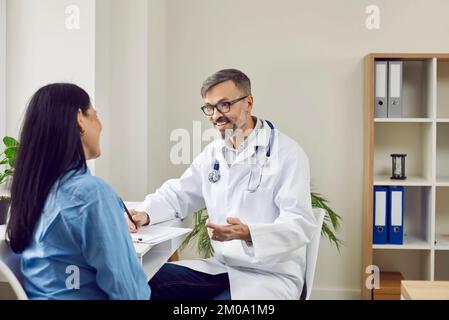 Doctor is talking to female patient and happily tells her good news about effectiveness of treatment Stock Photo