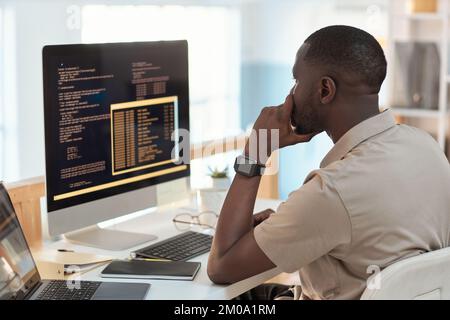 Pensive software engineer checking programming code on computer screen Stock Photo