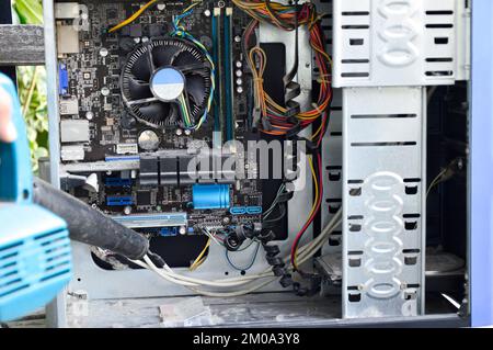Photograph of a technician blowing dust from a computer Stock Photo - Alamy