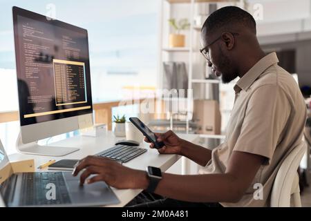 Software developer checking messages and notifications on smartphone Stock Photo