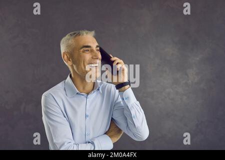 Happy smiling senior man experiencing positive emotions while talking on mobile phone. Stock Photo