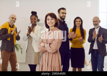 Portrait of confident middle-aged woman on background of her successful business team. Stock Photo