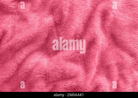 New soft red throw blanket with waves in color of the year 2023 Viva Magenta. Abstract fabric texture background with waves. Top view, close up Stock Photo