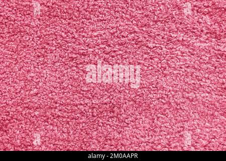 New soft red curly teddy fleece plush throw blanket or pillow case in color of the year 2023 Viva Magenta. Abstract fabric texture background with curles. Top view, closeup Stock Photo