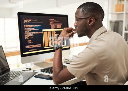 Pensive software engineer reading programming code on laptop screen Stock Photo