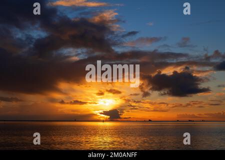 Sunrise cloudscape over the Baltic Sea with sun shining through rain clouds and reflection in water, northern Poland. Stock Photo