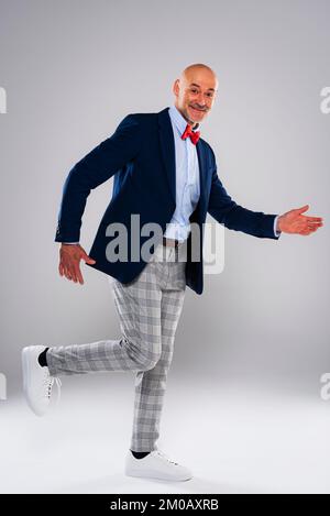 Full length of funny faced man walking against isolated white background. Smiling caucasian man wearing blazer and checked trousers. Copy space. Stock Photo