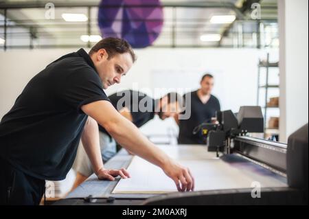 Professional workers graphic technicians operators work in a printing press and print shop with many different types of machines Stock Photo