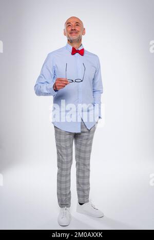 Full length of confident man standing at isolated white background. Smiling caucasian male wearing bow tie and checked trousers. Copy space. Stock Photo