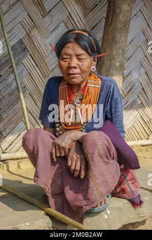 Mon district, Nagaland, India - 03 11 2014 : portrait of squatting old Naga Konyak tribal woman wearing necklace and porcupine quills in her ears Stock Photo