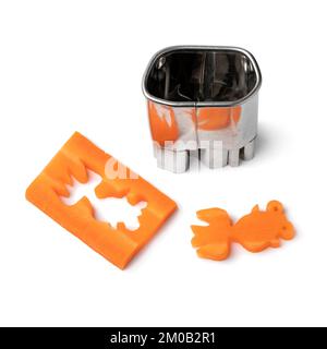 Cutting out agoldfis from a fresh raw sweet winter carrot slice with a metallic mold  for decoration on white background Stock Photo