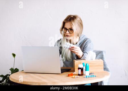Portrait of young woman showing pills blister to screen, having video call with doctor online, taking prescription. Stock Photo