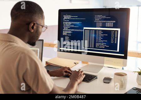 Black developer in glasses debugging software when working on computer in office Stock Photo