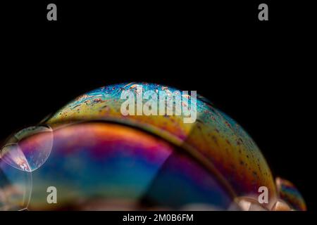 A closeup of soap bubble with rainbow colors on a dark background Stock Photo