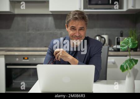 Portrait of businessman. Older man tele working with laptop computer at home office in living room. Stock Photo