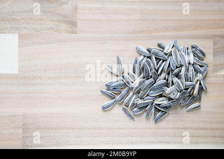 Roasted and salted dry snack sunflower seeds with hulls put randomly on a wooden surface Stock Photo