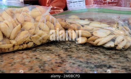 Close-up of two plastic zip bags with roasted salted peanuts and roasted salted pumpkin seeds on kitchen counter packed for snacking, hiking, camping. Stock Photo
