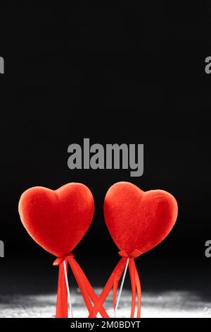 Valentine's Day, two red loving hearts on a black background with sequins. Stock Photo