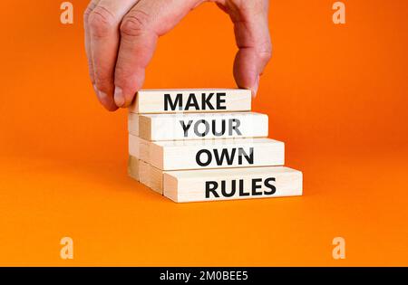 Make your own rules symbol. Concept words Make your own rules on wooden cubes. Beautiful orange table orange background. Businessman hand. Business mo Stock Photo