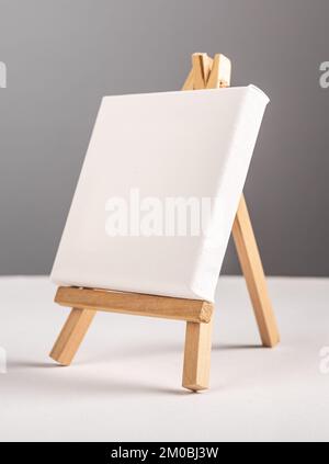 Empty blank white canvas mockup standing on mini wood tripod easel on desk. High quality photo Stock Photo