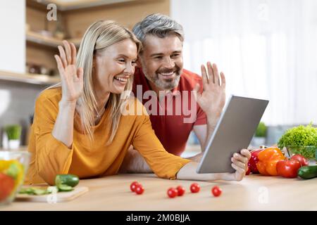 Cheerful mature man and woman cooking and having video call Stock Photo