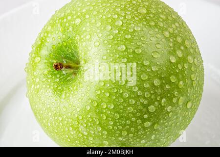 Fresh green apple with water drops macro. Close-up of water droplets on organic fruit. Ripe juicy apple for vitamin vegetarian snack. Close-up. Stock Photo