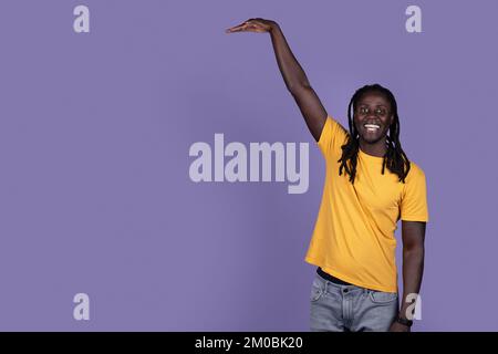 Cheerful african american guy showing height of something invisible Stock Photo