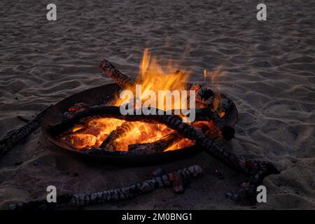 Bonfire on a beach. Gathering by the fire at sunset. Holiday activity. Stock Photo