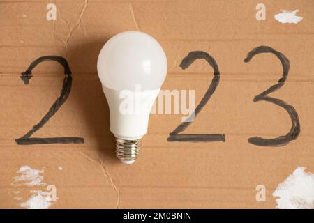 Led light bulb and written year 2023 on brown paper ,new technology in the new year,light Stock Photo