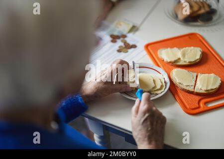 Close-up of the hands of an elderly woman making sandwiches in the kitchen Stock Photo