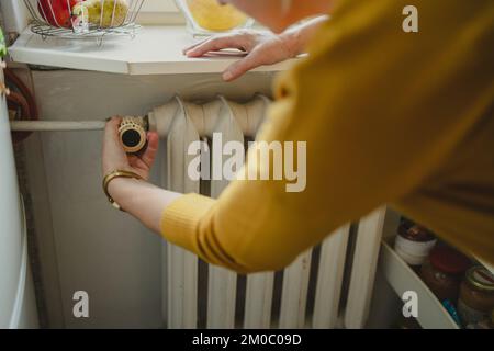 Woman adjusting the temperature of a radiator at home Stock Photo