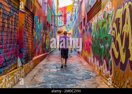 Goiânia, Goias, Brazil – December 04, 2022: A man, from the back, walking along the corridor of Beco da Codorna, a picturesque place in the city of Go Stock Photo