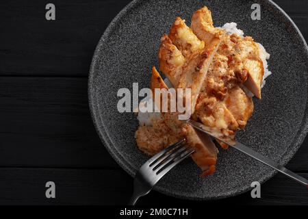 A man is eating an Indian dish. Hands holding knife and fork. Indian chicken with butter and basmati rice in a plate. .Black background. Place for Stock Photo