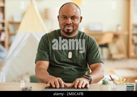 Warm toned portrait of adult black man using computer at home and looking at camera POV Stock Photo