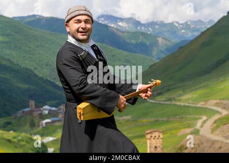 Georgian man from Svaneti region playing national musical instrument of Panduri and singing local songs in Ushguli, Caucasus Mountains, Georgia. Stock Photo