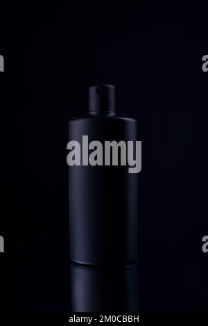 black shampoo bottle on black background still life Stock Photo