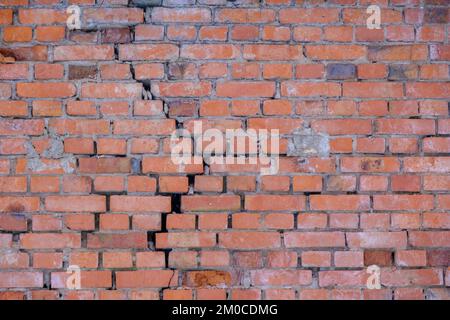 Cracked red brick wall. Brick wall background. Stock Photo