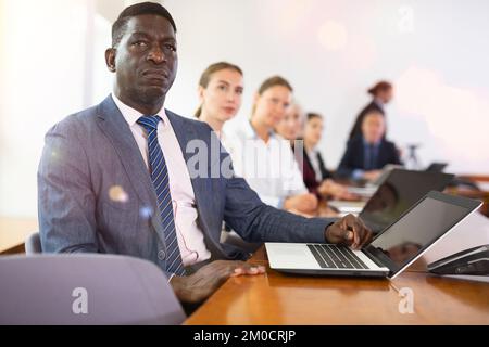 Mature african businessman sitting at meeting and listening to colleague's report Stock Photo