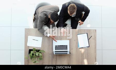 Two successful smiling businessmen are working on a laptop. view from above Stock Photo