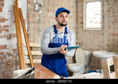 Foreman making task list during works in building under construction Stock Photo