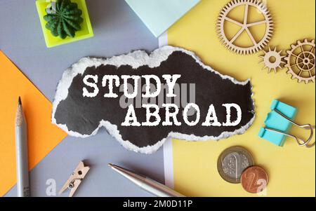 The text Study Abroad appearing behind torn brown paper. Stock Photo