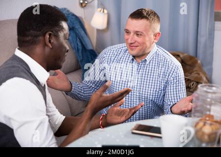 Two smiling male friends with smartphones and talking Stock Photo