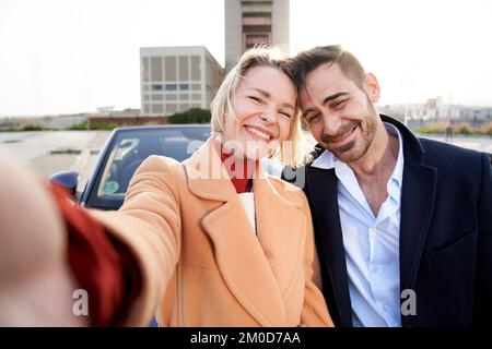 Cheerful middle-aged marriage taking selfie looking at camera. Smiling and happy couple having fun Stock Photo