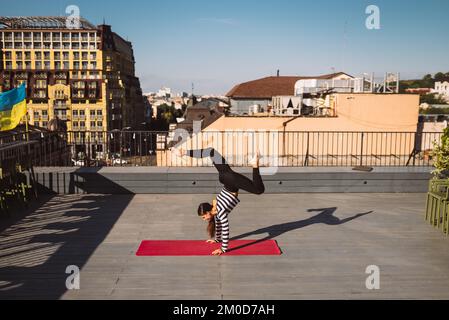 Young woman working out outdoors and doing yoga handstand exercise Stock Photo