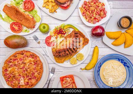A set of dishes with recipes from Caribbean gastronomy, with many plantains, empanadas, pizza with pineapple, salchipapas, fried pork rinds and assort Stock Photo