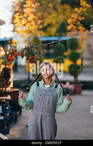 Playful farmer woman in denim overalls smiling sincerely while posing. Stock Photo