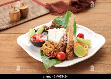 Nasi Campur Bali, Indonesian Balinese Mix Rice with Sate Lilit, Ayam Sisit, Sambal Matah, and Peanut Stock Photo