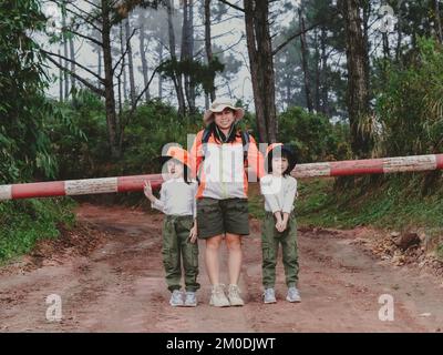 Happy young woman with her daughter walking on a field trip together in the mountains. Family on a hiking adventure through the forest. Parents teach Stock Photo